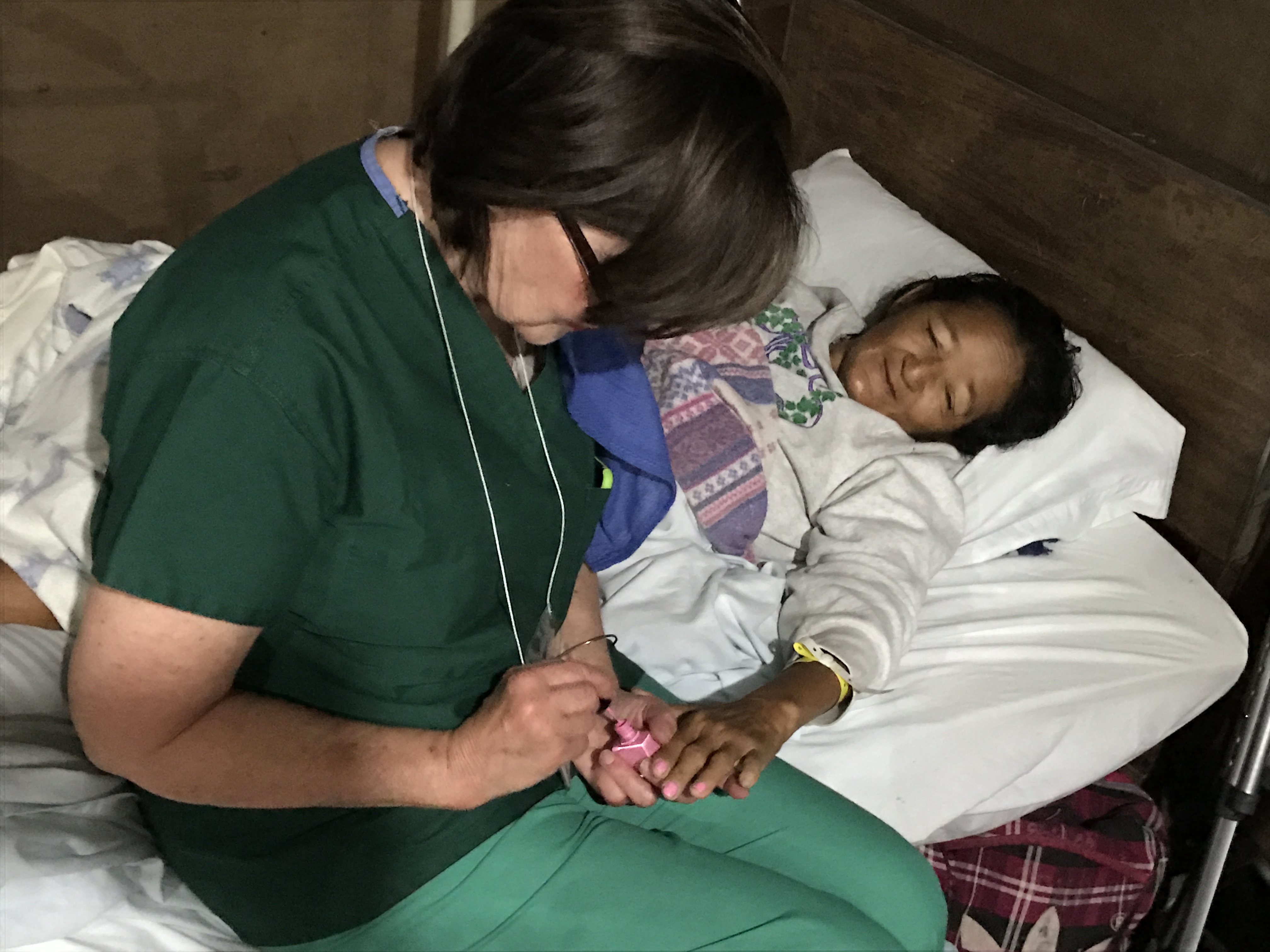 Voluntaria y donante de Operation Walk pinta las uñas de una de las pacientes