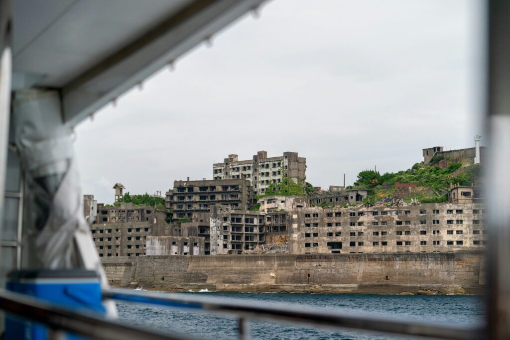 View from a boat showing the abandoned and decaying concrete buildings on Hashima Island (Gunkanjima) near the coast of Nagasaki, Japan.